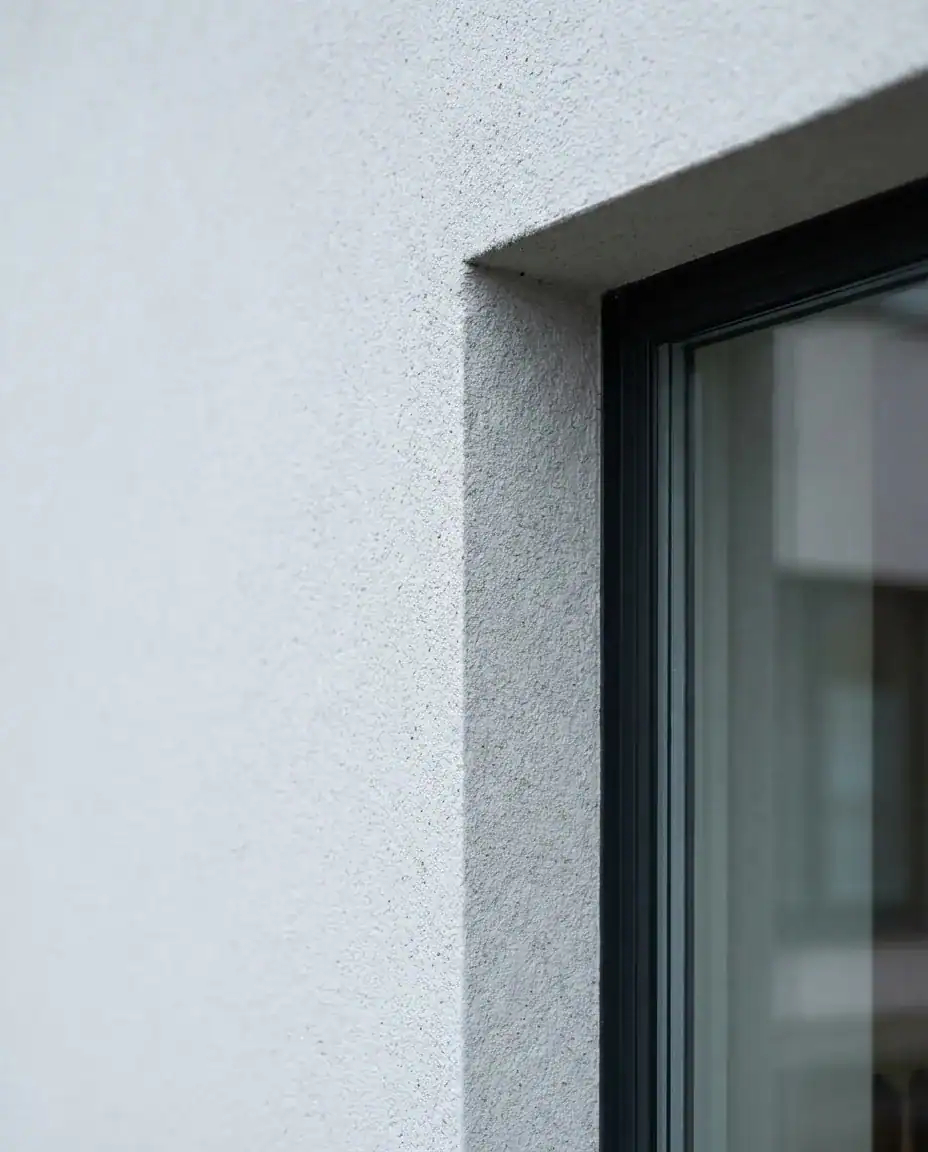 Nærbilde av en profesjonelt utført pussfasade med detaljer rundt et vindu